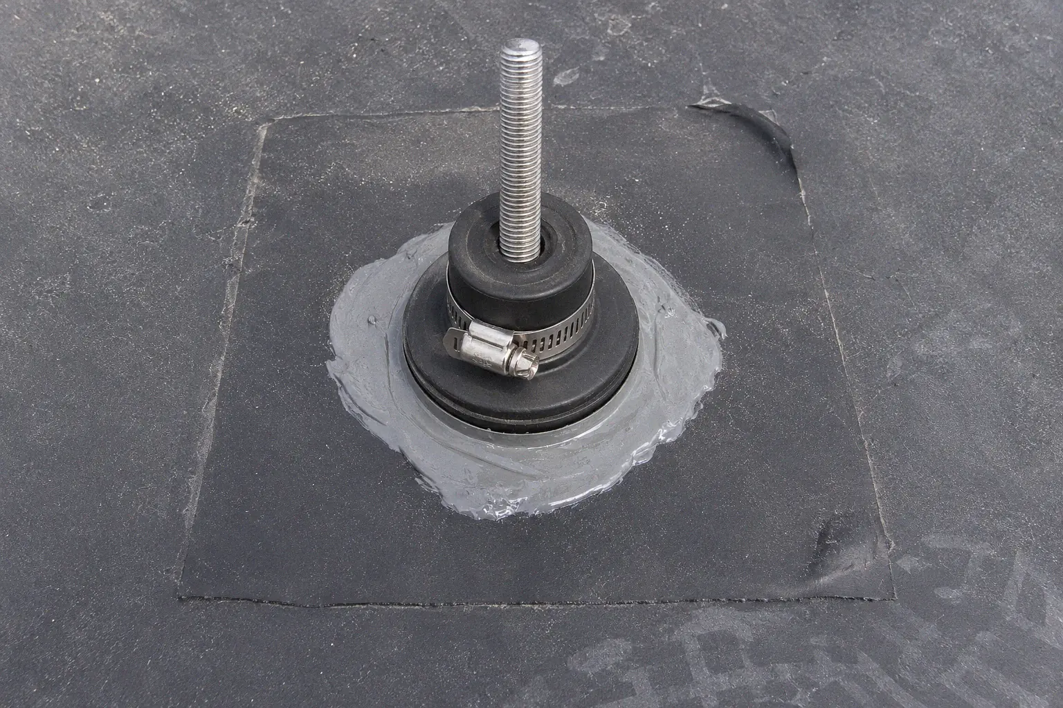 EPDM flashing boot and rubber patch sealing a penetrating solar mount