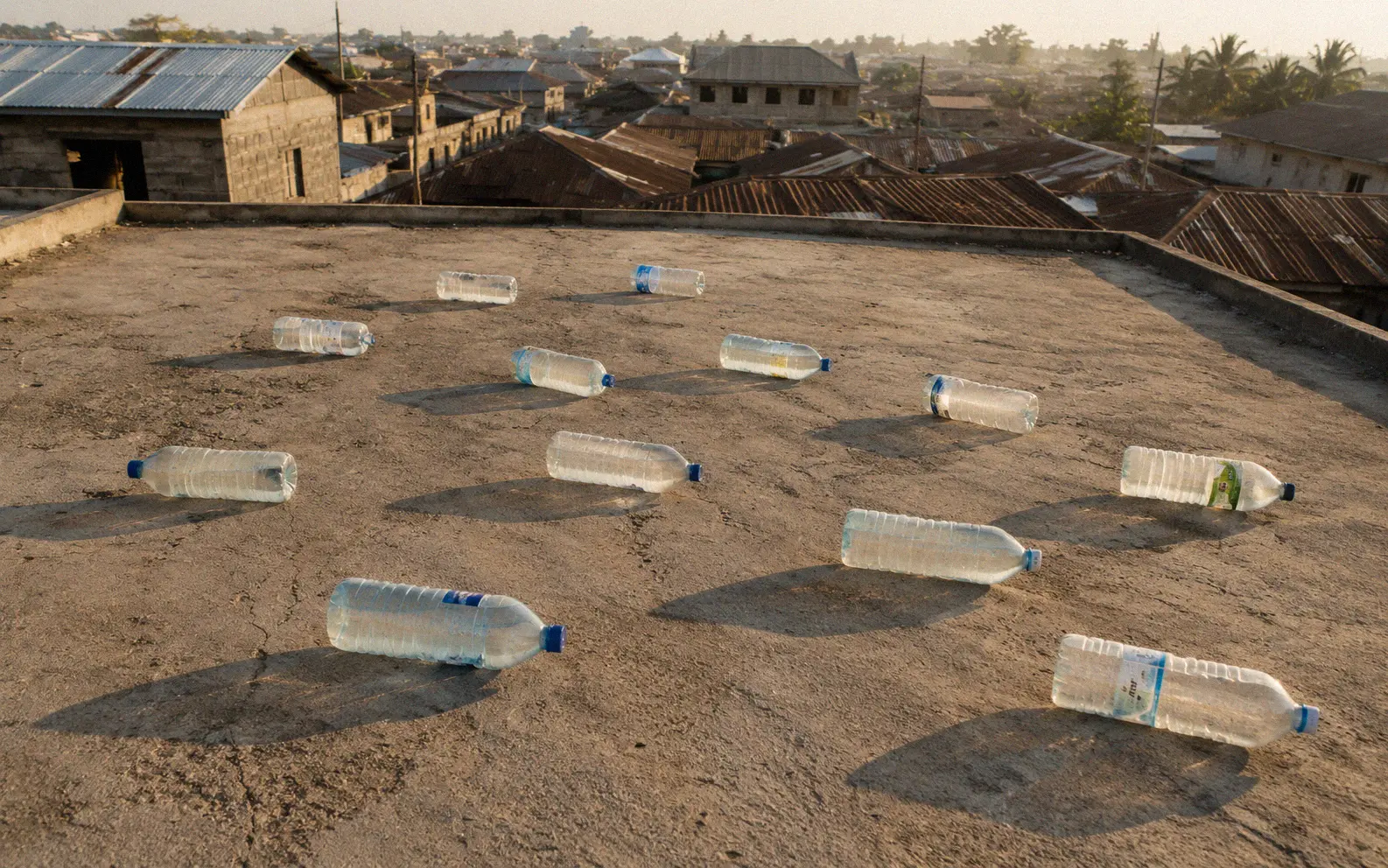 Clear water bottles sitting in sunlight on a rooftop for solar disinfection treatment