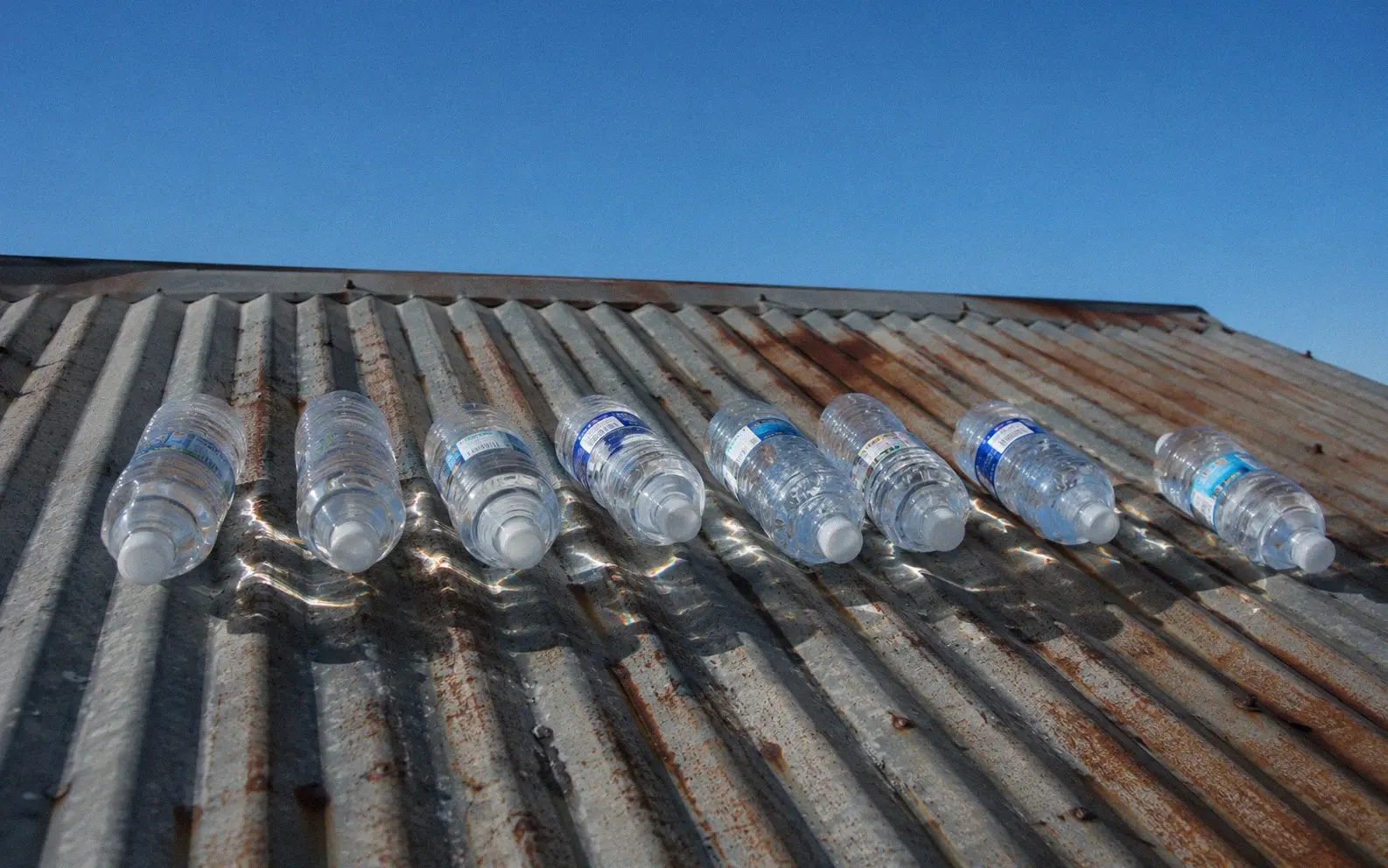 Water bottles positioned on their sides on a rooftop receiving direct afternoon sunlight