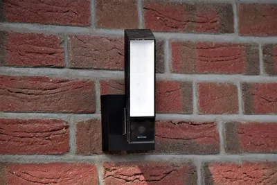 Solar security flood light mounted above a garage door