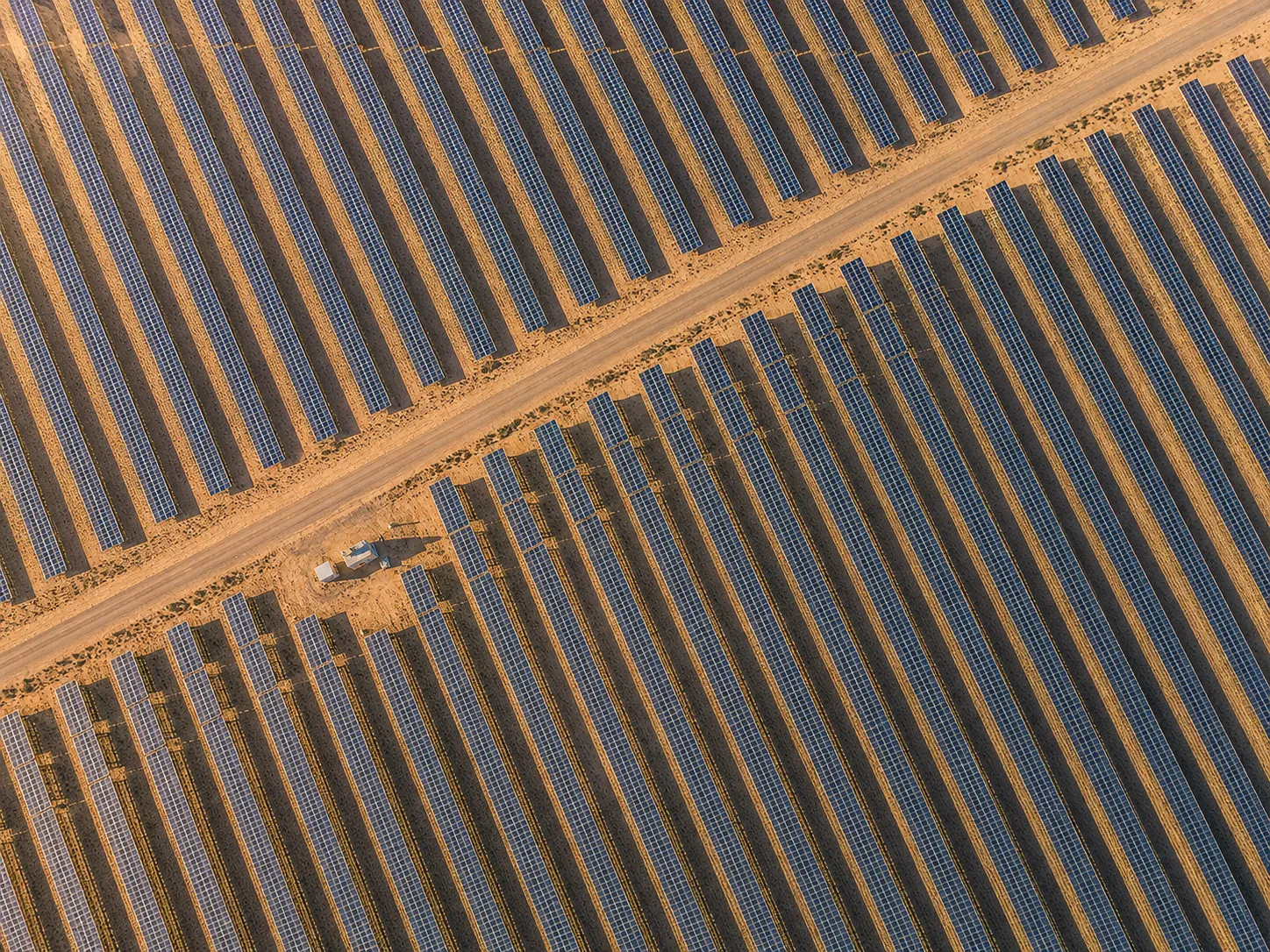 Workers inspecting solar panels at a quality control station in a manufacturing plant